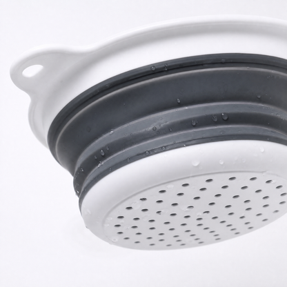 Macro close-up of the colander's perforated bottom and ribbed grey silicone folds.