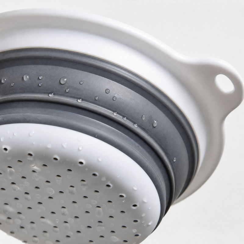 Close-up of the colander's perforated bottom and ribbed grey silicone folds.