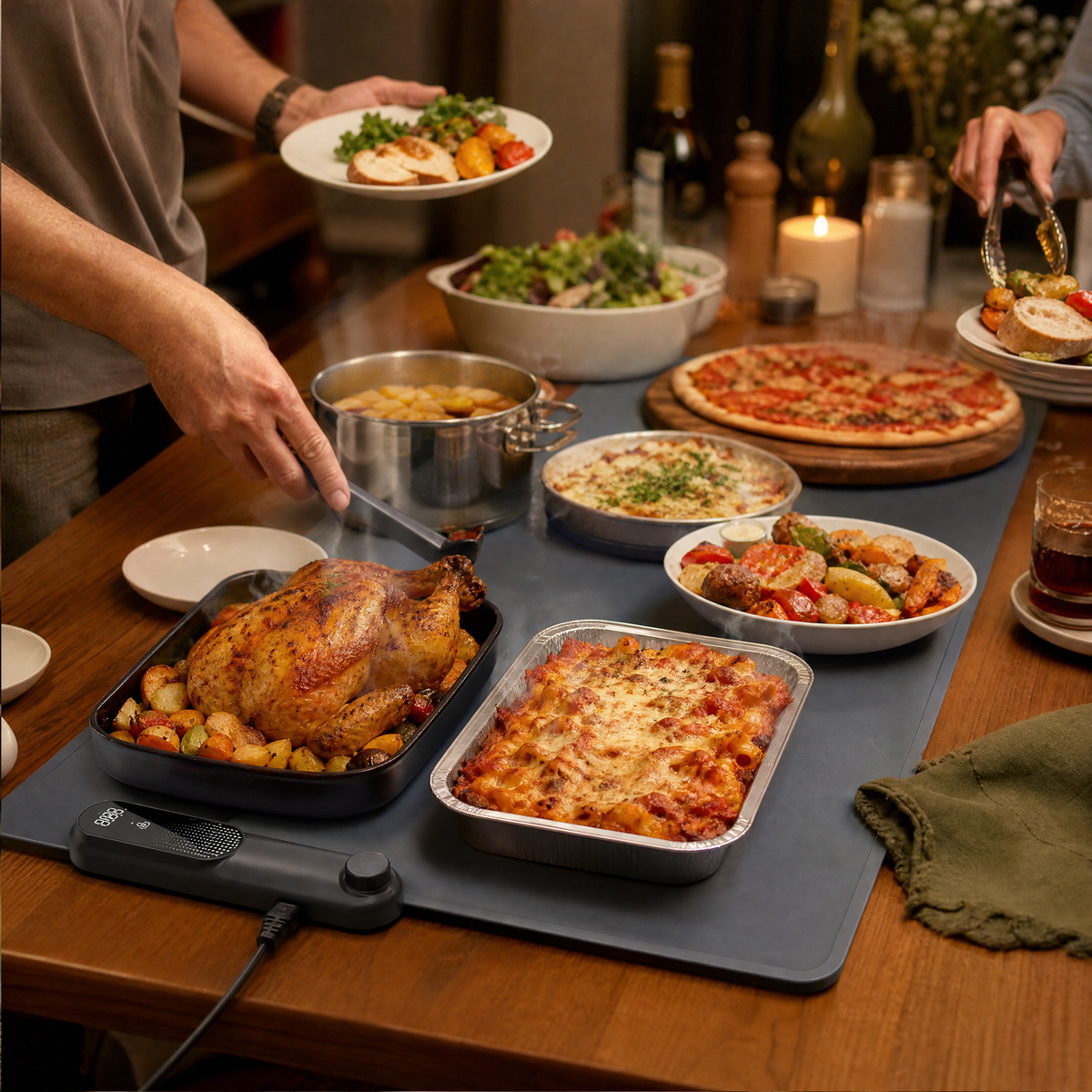 A food warming mat running along a party buffet table full of hot dishes with a host serving.