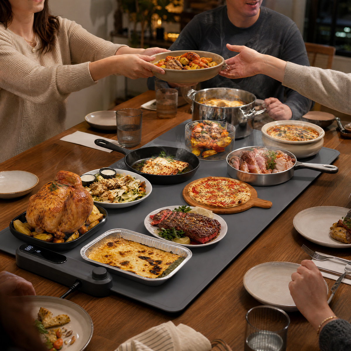A food warming mat fully loaded with pots, pans, plates and trays at a family dinner table.