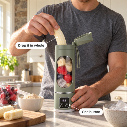 A man drops a whole banana into a sage green portable blender on a kitchen counter next to protein powder and frozen berries.